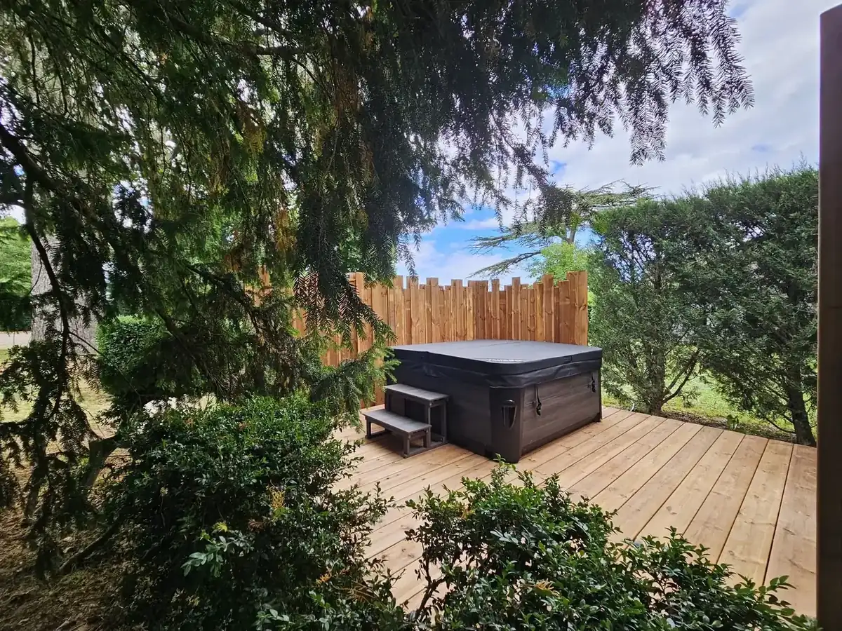 Spa extérieur sur terrasse bois entourée de végétation